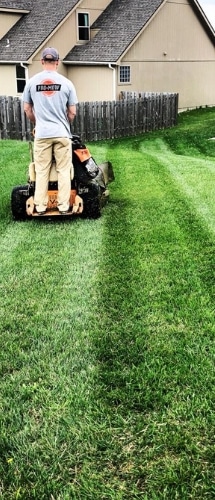 A Pro Mow employee in the process of mowing a lawn. 
