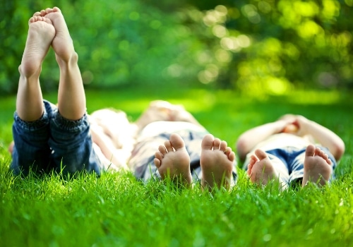 Three young children laying in the grass together. 